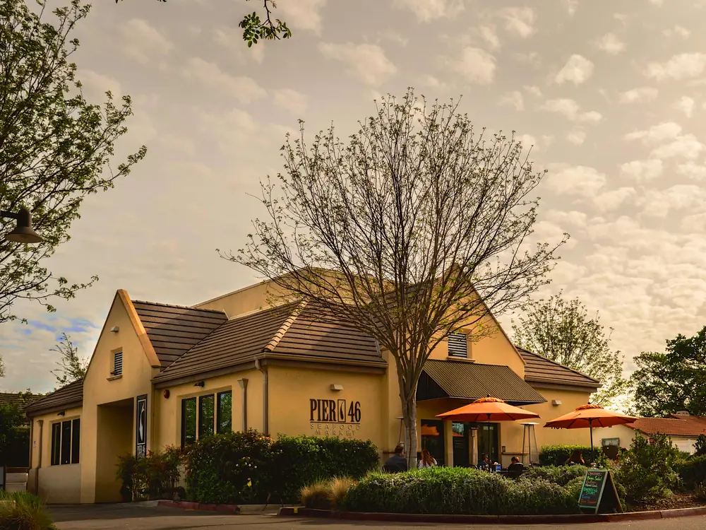 The Pier 46 storefront in the Vineyard Center, with orange umbrellas over the patio tables